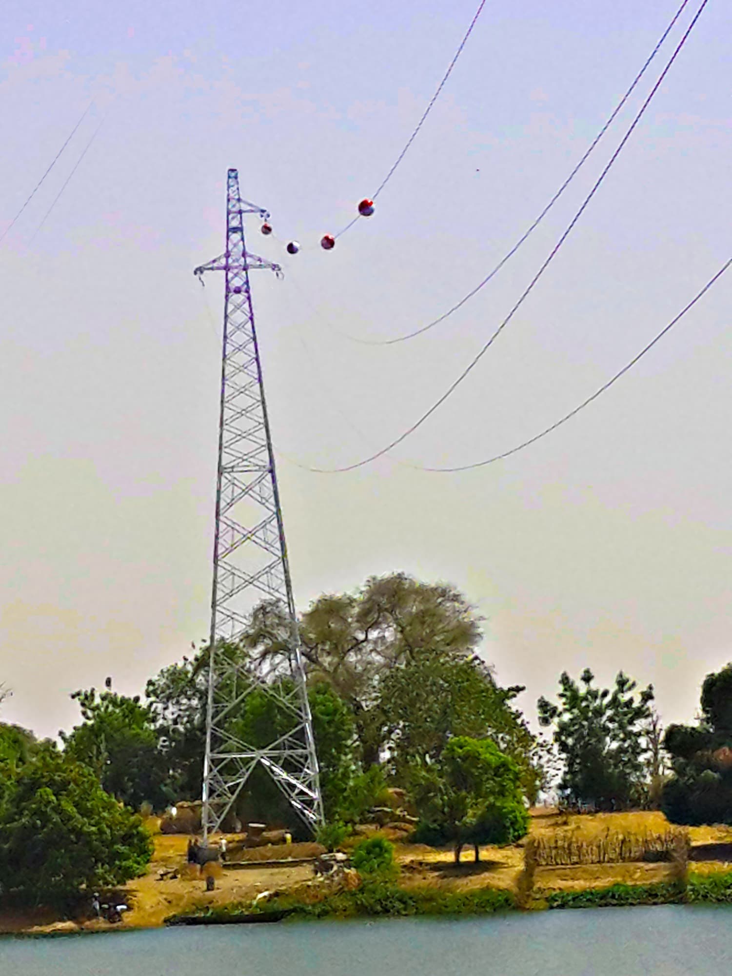 Pylône de la ligne haute tension du réseau interconnecté franchissant un cours d'eau, balises de signalisation aérienne sur le câble de garde