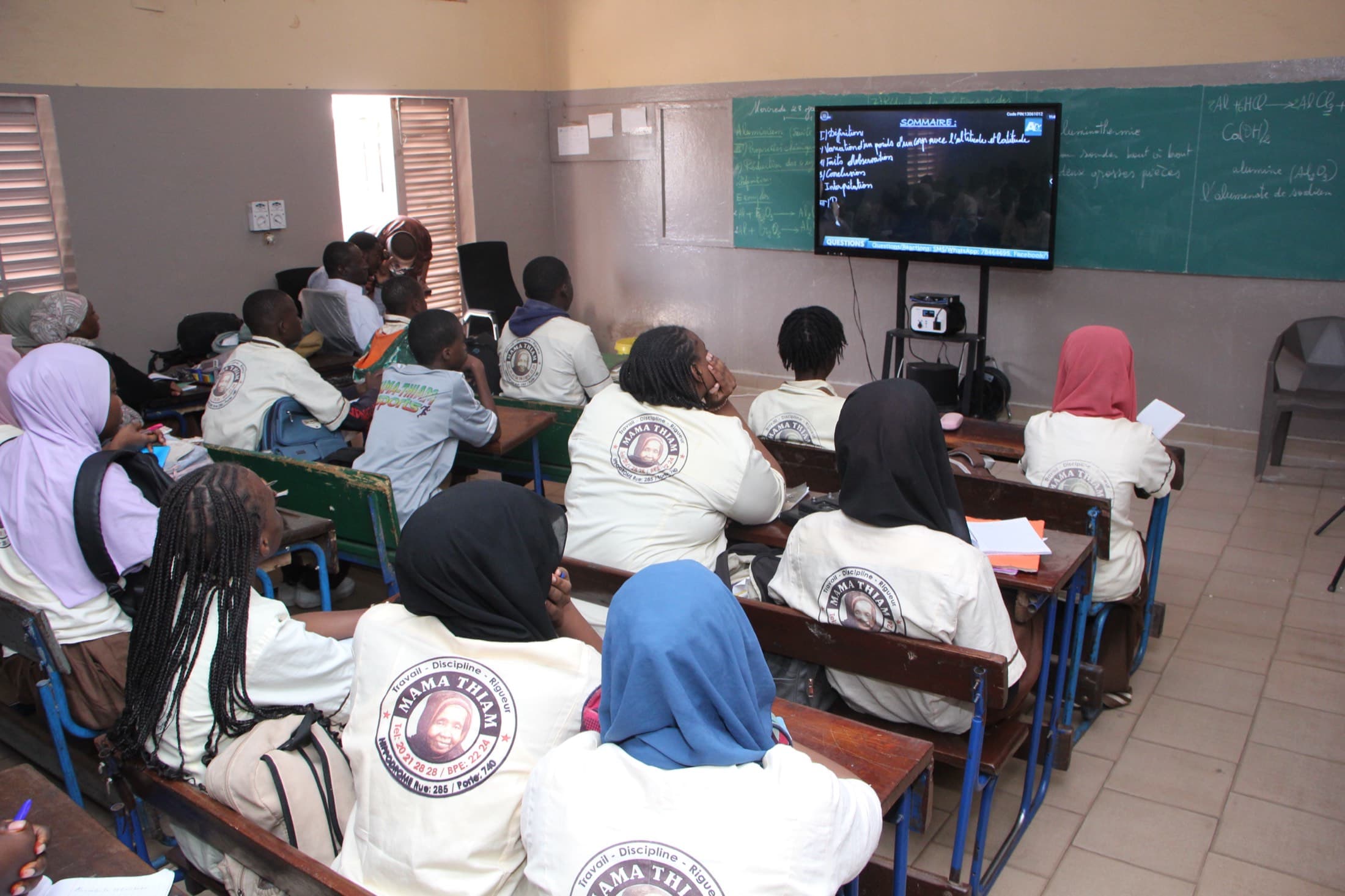 Élèves suivant un cours en classe, filles et garçons réunis devant l'écran
